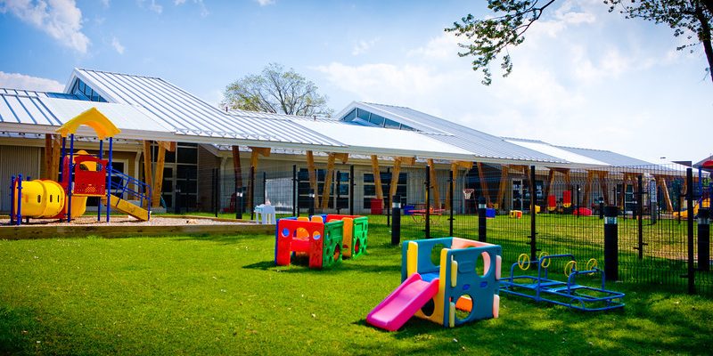 Play area with green grass, a small slide, a playground
