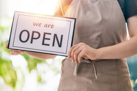 Small-business-owner-holding-a-We-are-open-sign