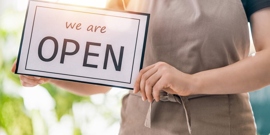 Small-business-owner-holding-a-We-are-open-sign